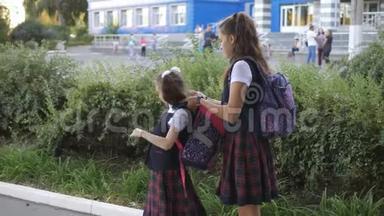 两个姐妹一起上学。 姐姐帮小妹背上背包..